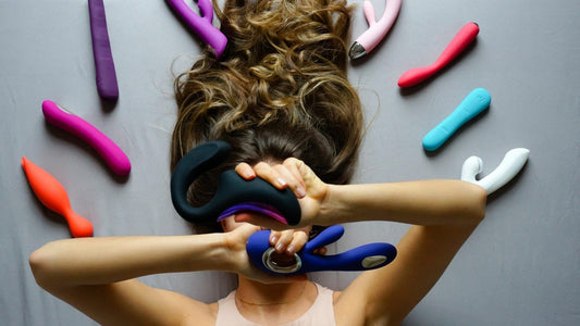 A girl holding a vibrator surrounded by many adult toys